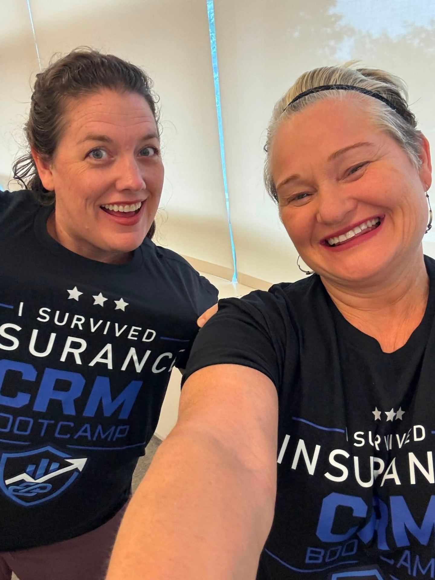 Two attendees laughing in their 'I Survived' bootcamp shirts